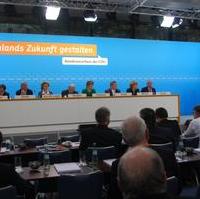 Bild vergrößern:Das Tagungspräsidium beim CDU-Bundesausschuss in Berlin. Nach rund 30 Wortmeldungen wurde dem Vertragsentwurf bei 2 Enthaltungen einstimmig zugestimmt. 