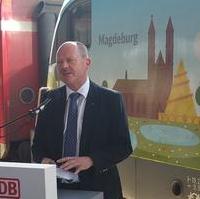 Bild vergrößern:Landesentwicklungsminister Thomas Webel bei der Vorstellung einer Lok mit Werbemotiven auf der auch Magdeburg verewigt ist.