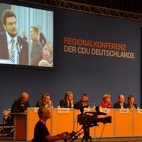 Bild vergrößern:Podium bei der CDU-Regionalkonferenz - auf dem Bildschirm zu sehen der CDU-Kreisvorsitzende Tobias Krull bei seinem Redebeitrag